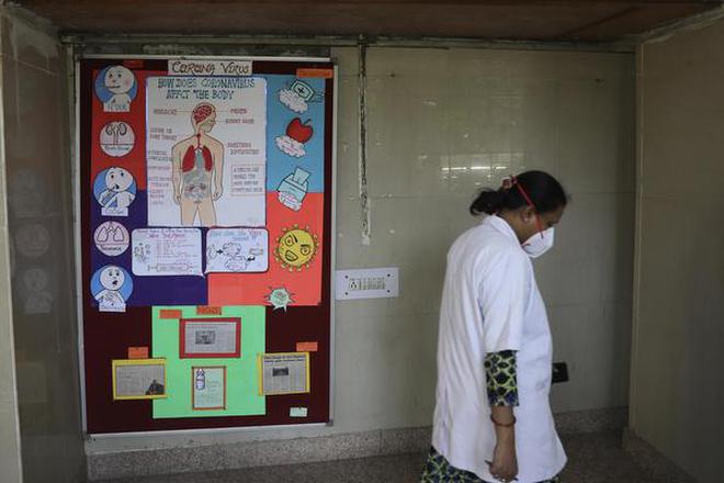 A doctor walks past coronavirus awareness posters displayed at a government-run hospital in New Delhi on March 13, 2020.