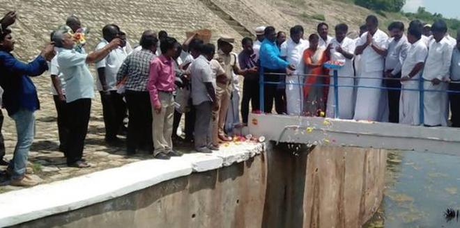 Warm welcome: Ministers S.P. Velumani and P. Benjamin offering flowers as water flows through the Kandaleru-Poondi canal.