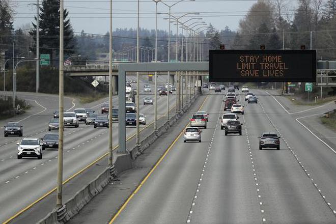 A sign on Interstate 5 advises people to stay home and limit travel as light early evening traffic heads north, Sunday, March 22, 2020, in Lakewood, Washington, near Tacoma. Officials are urging people to stay home except for essential trips out in hopes of slowing the outbreak of the new coronavirus.