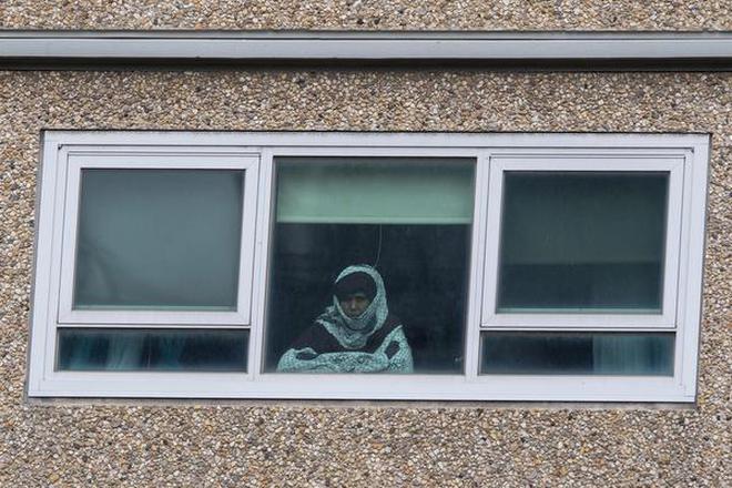 A woman looking out of a window from a locked-down public housing tower in Melbourne.
