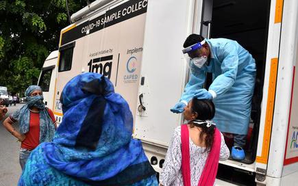 A health worker collects swab sample for coronavirus test at a mobile testing van, in New Delhi. File