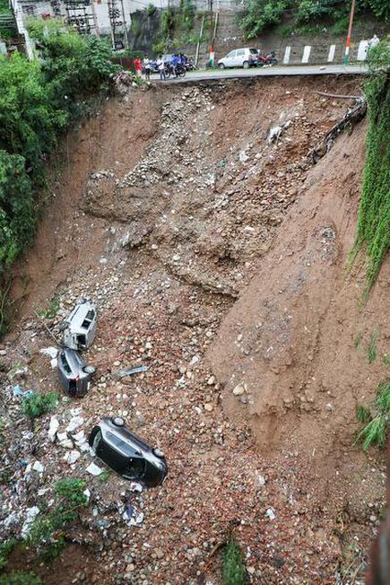 Vehicles lie buried in landslide rubble after a portion of a road caved-in following heavy rainfall, in Jammu, on Aug. 17, 2020.