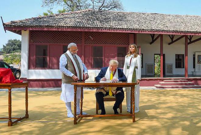 U.S. President Donald Trump signs the visitors’ book as Prime Minister Narendra Modi and First Lady Melania Trump looks on, at Sabarmati Ashram, in Ahmedabad.