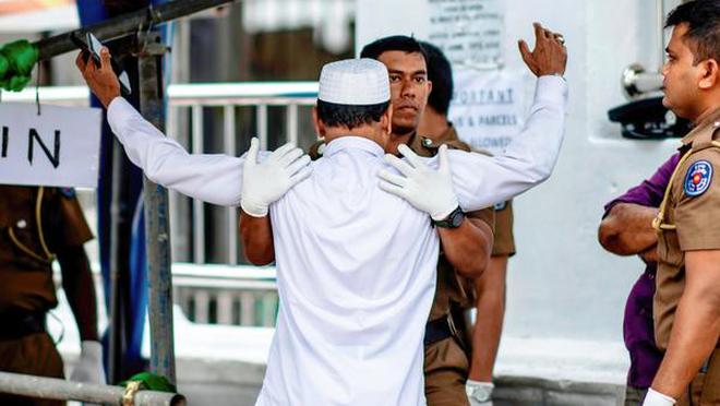 A policeman frisks a devotee as he arrives at a mosque to attend prayer in Colombo after the bomb blasts on April 21.